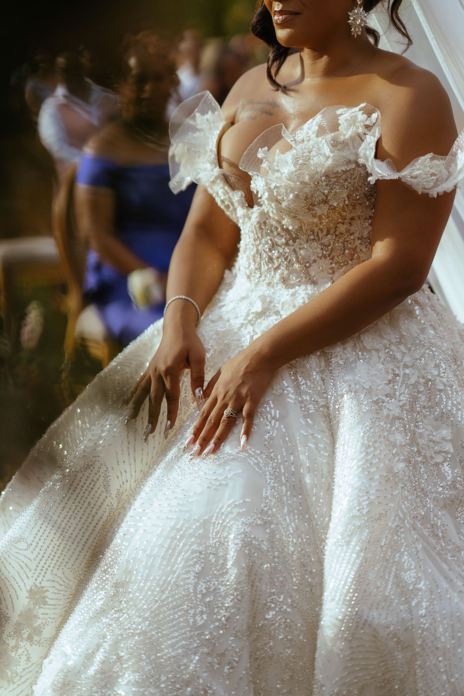 Detailed view of an ornate white wedding dress with intricate beading and off-shoulder design.
