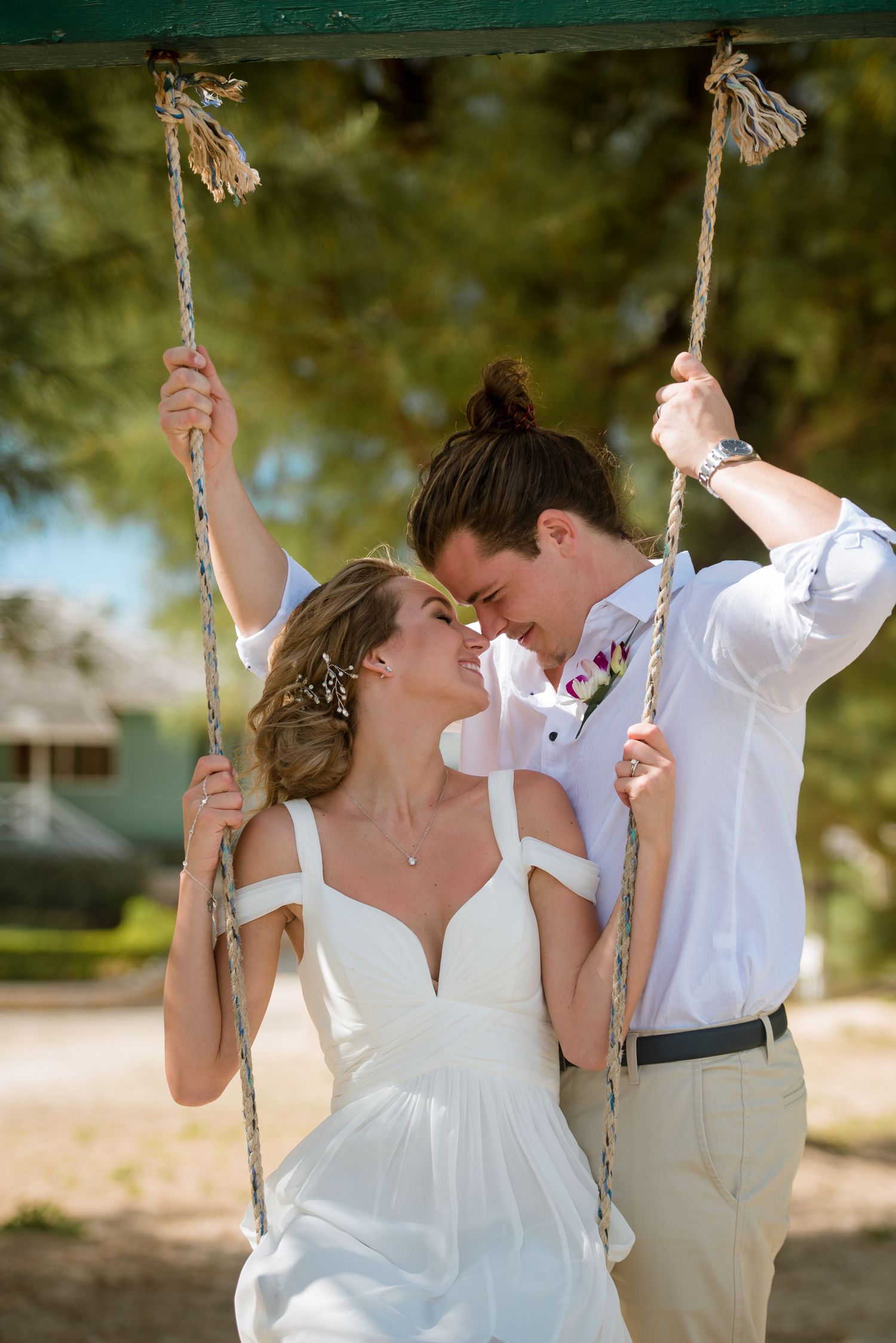 Couple shares intimate moments on swing set during outdoor wedding photo session.