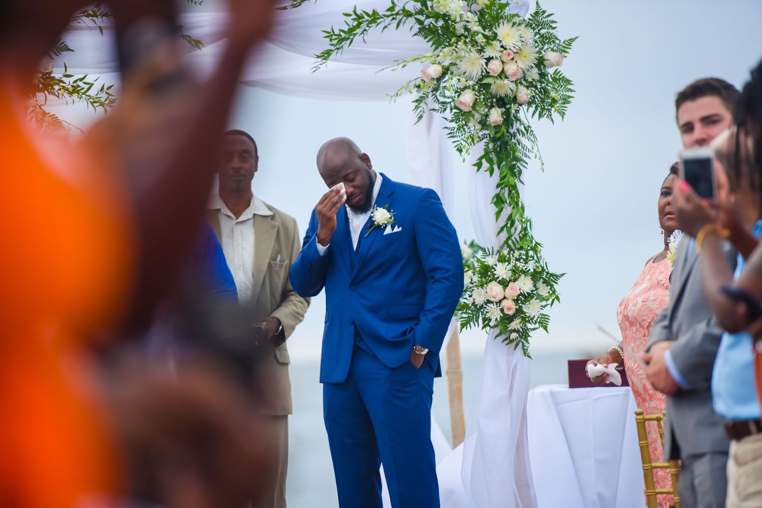 Emotional wedding ceremony moment under a floral arch with elegant white and green decorations.