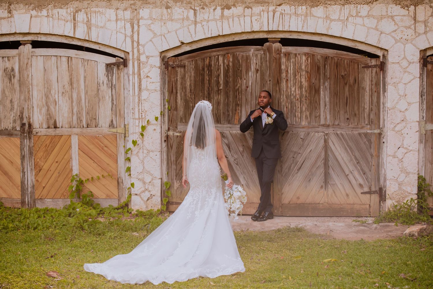 Elegant wedding scene against weathered wooden barn doors and stone walls.
