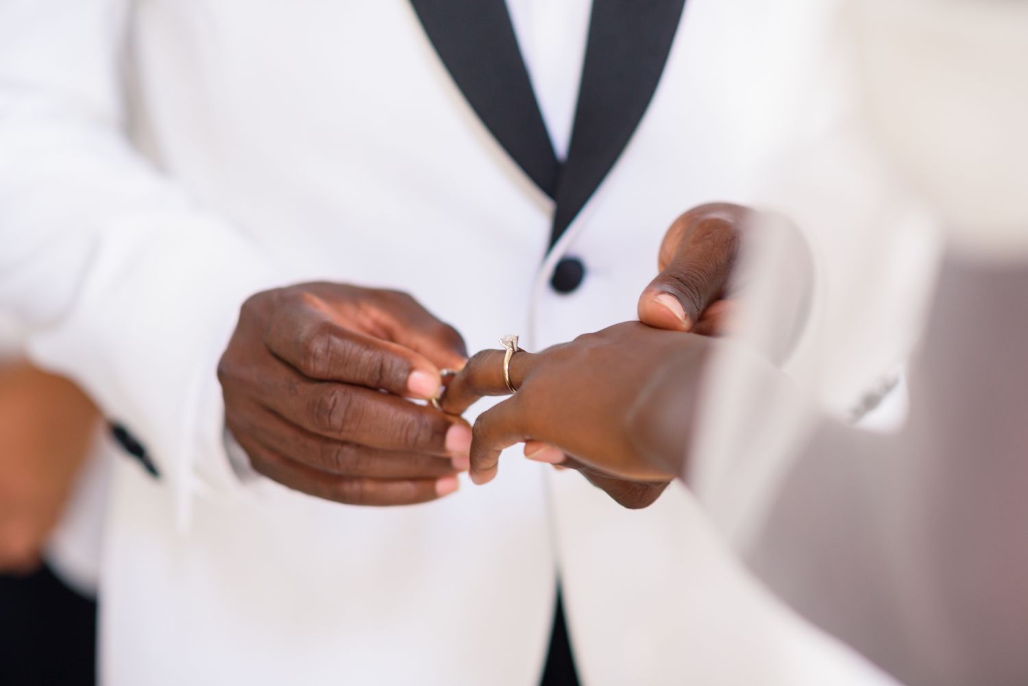 Close-up of hands exchanging rings during wedding ceremony.