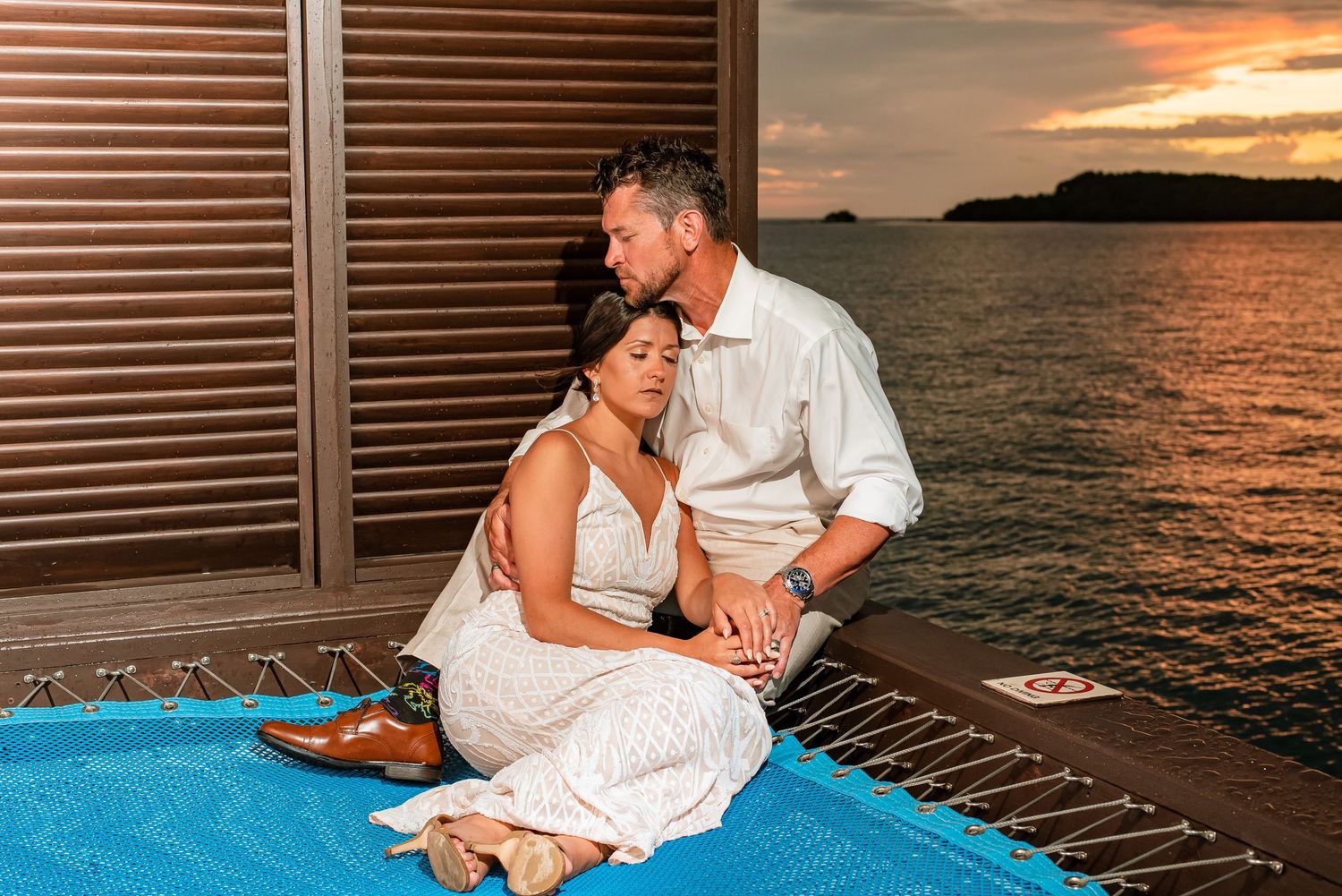 Couple shares intimate moments by infinity pool during sunset wedding reception.