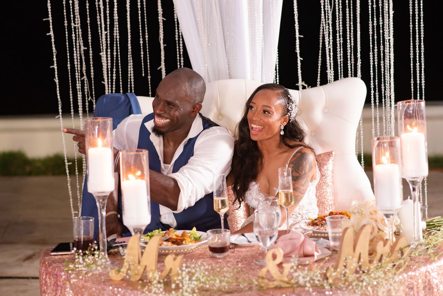 Elegant table setting with candles and white decor at a wedding reception.