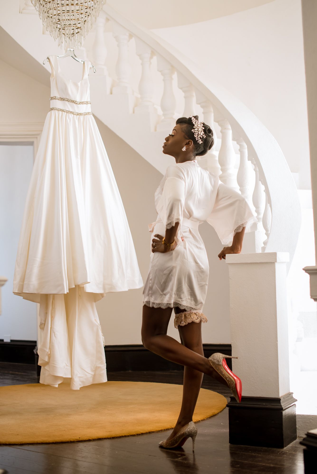 A playful moment captured of someone in white bridal preparation attire near a hanging wedding dress.