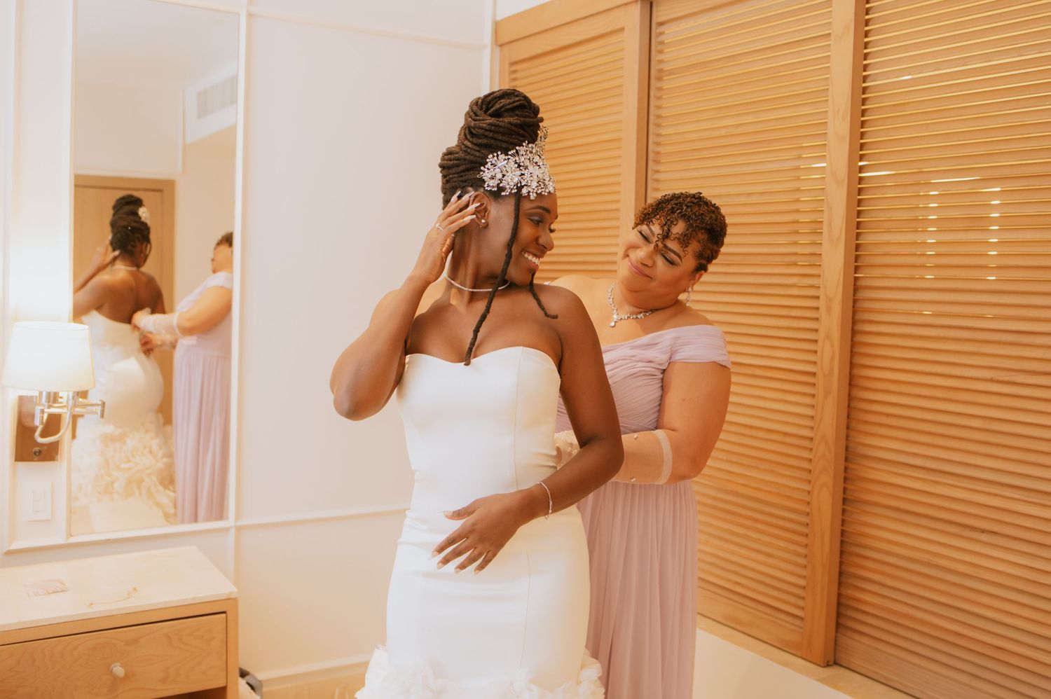 Behind-the-scenes moment of bride getting ready with help from bridesmaid.