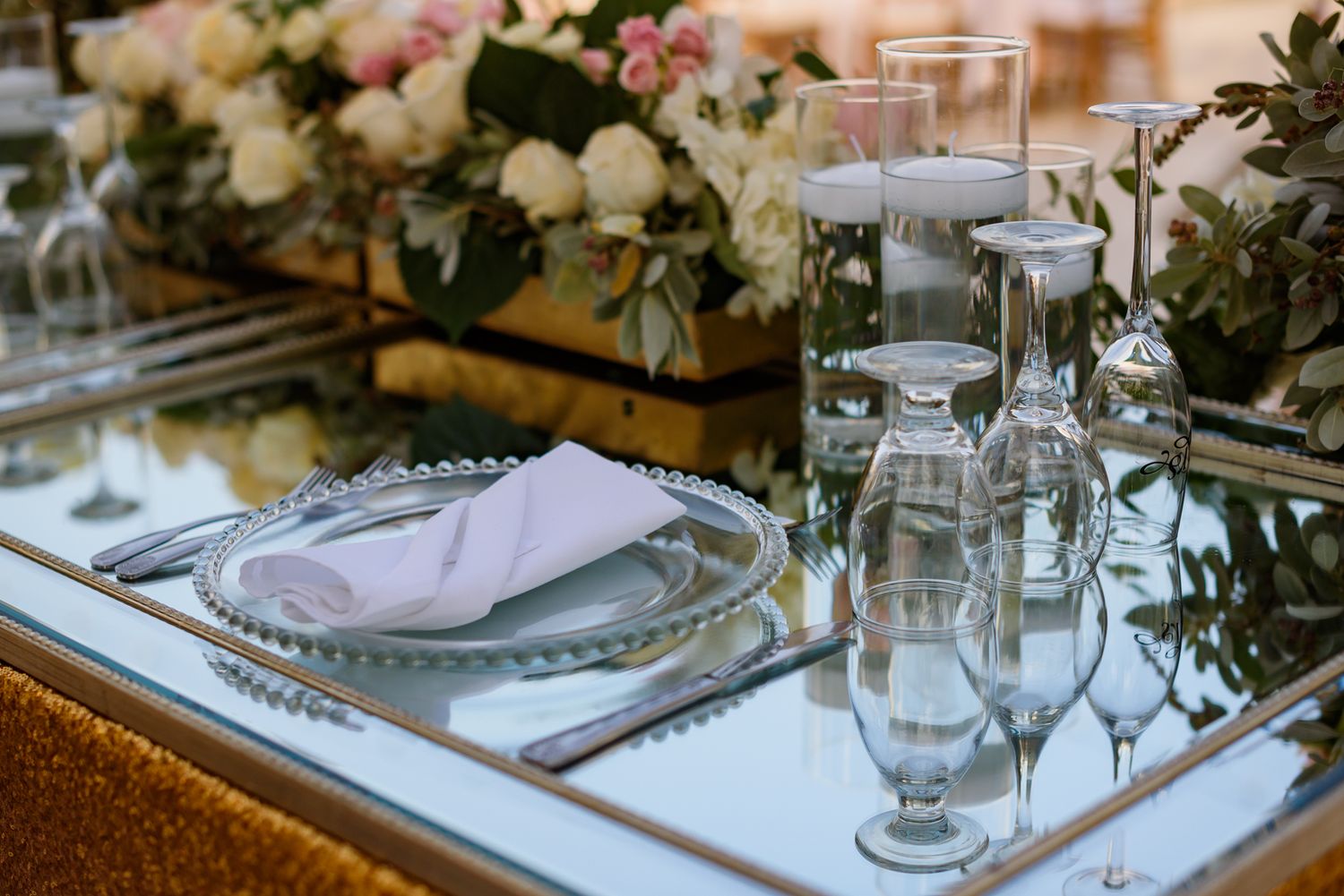 Close-up of formal dining table with crystal glassware and floral arrangements.