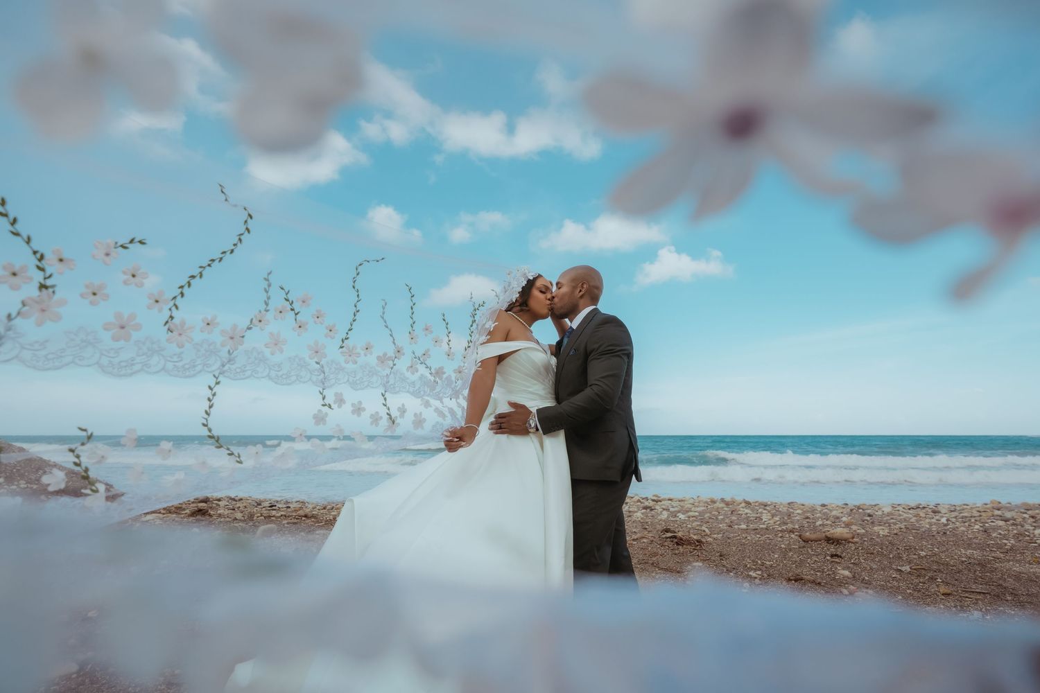 Dreamy beach wedding scene with flowing veil and ocean backdrop.