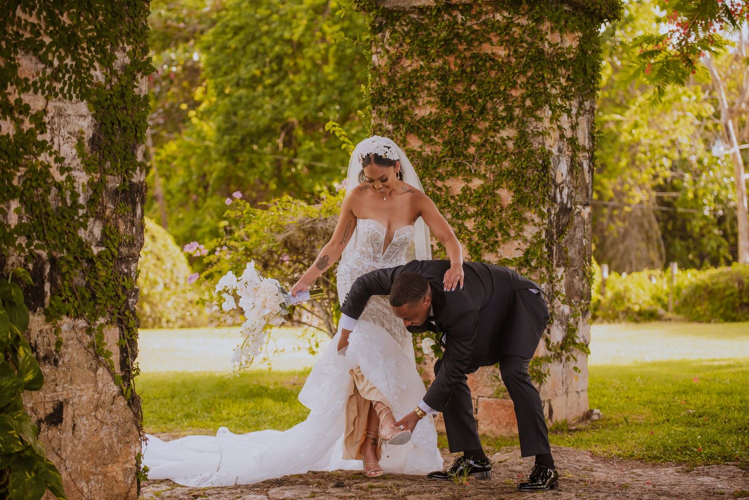 A romantic wedding couple shares an intimate moment in a lush garden setting during golden hour.