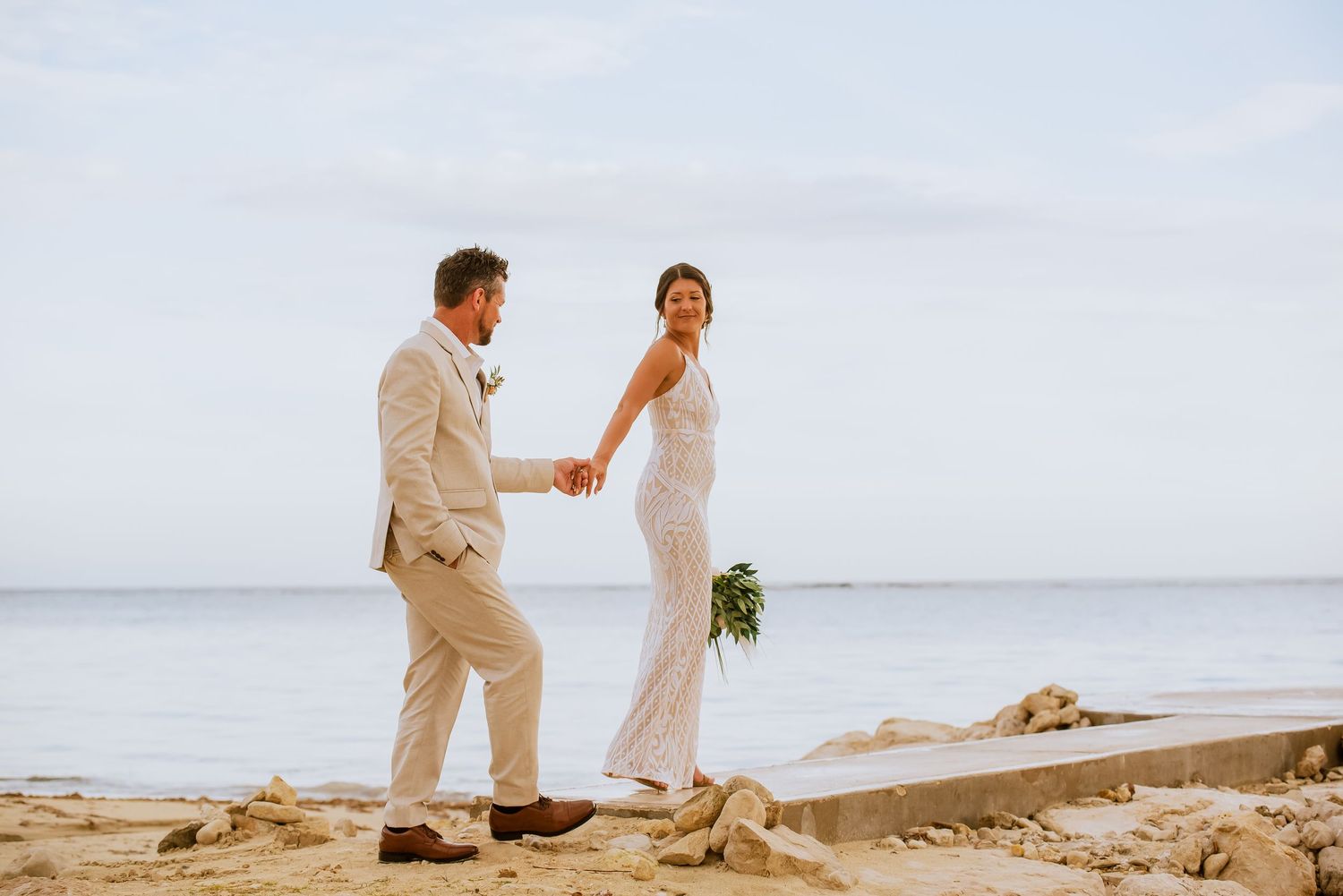 Wedding couple dances together on a circular platform overlooking the ocean.