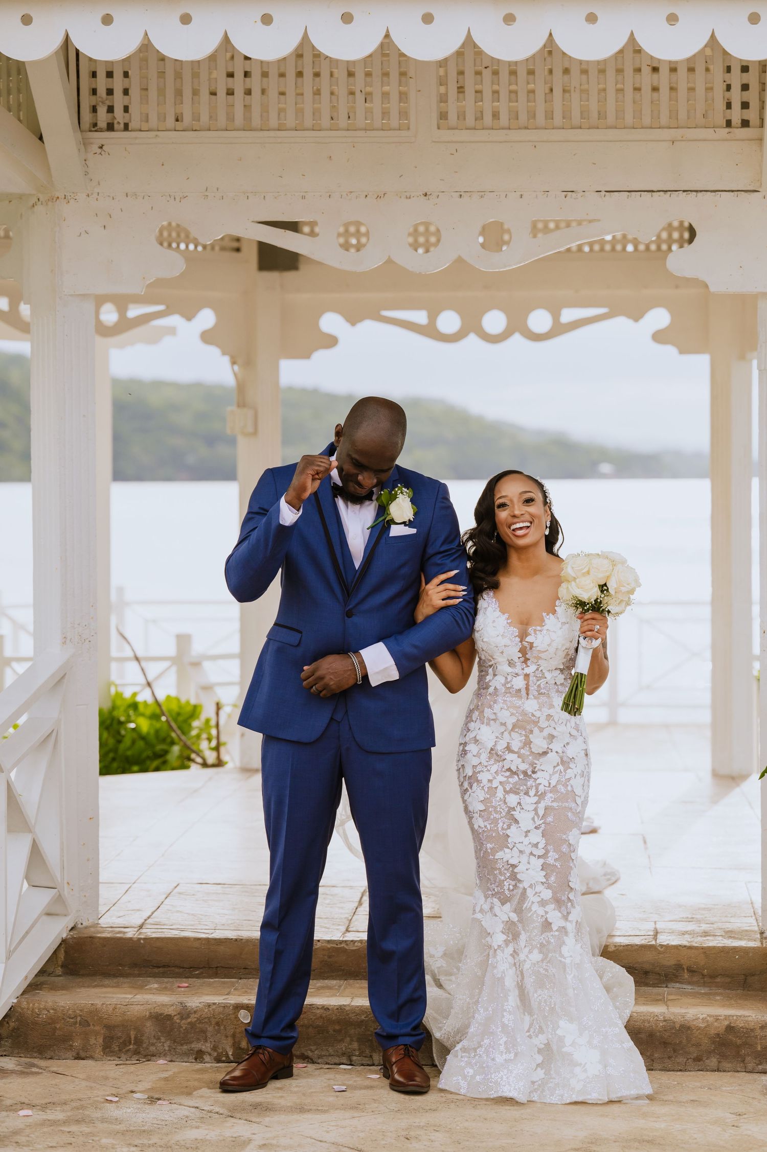Joyful newlyweds share a celebratory moment in a waterfront gazebo.
