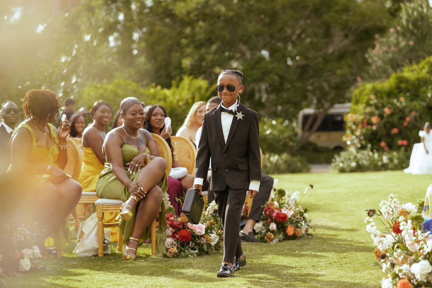 Outdoor wedding ceremony setup with floral arrangements and seated guests in a garden setting.