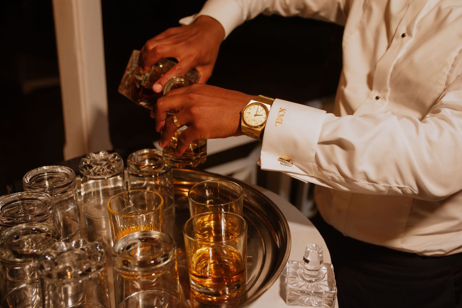 Close-up of bartender pouring craft cocktails at elegant reception bar.