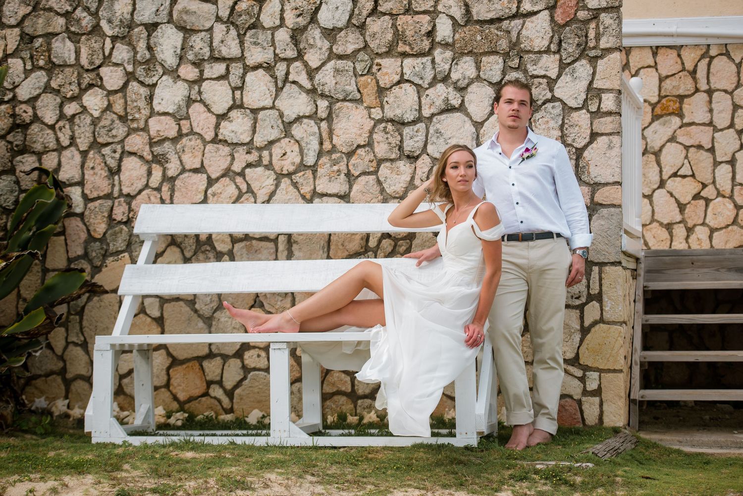 Romantic wedding portraits against rustic stone wall backdrop near the beach.