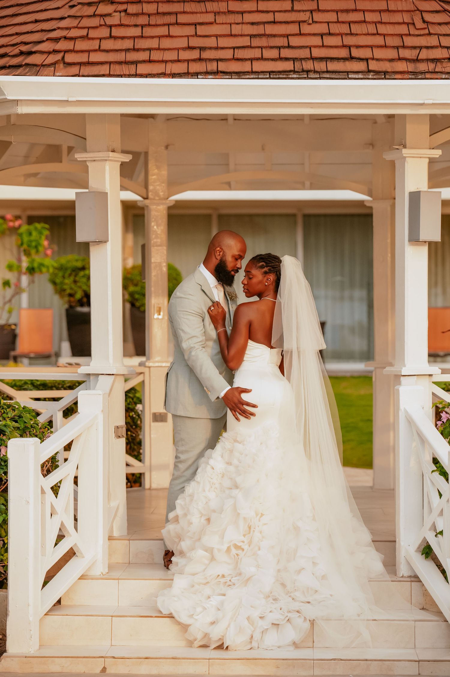 A series of romantic wedding poses captured on a white porch with terracotta roof tiles.