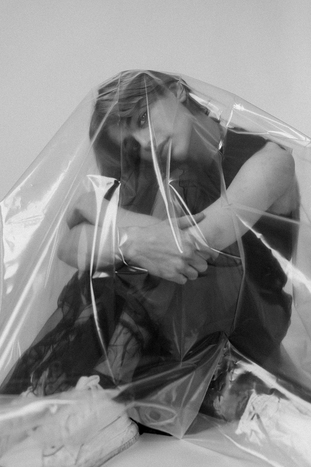 A sequence of black and white photos shows someone moving under a transparent plastic sheet or covering.