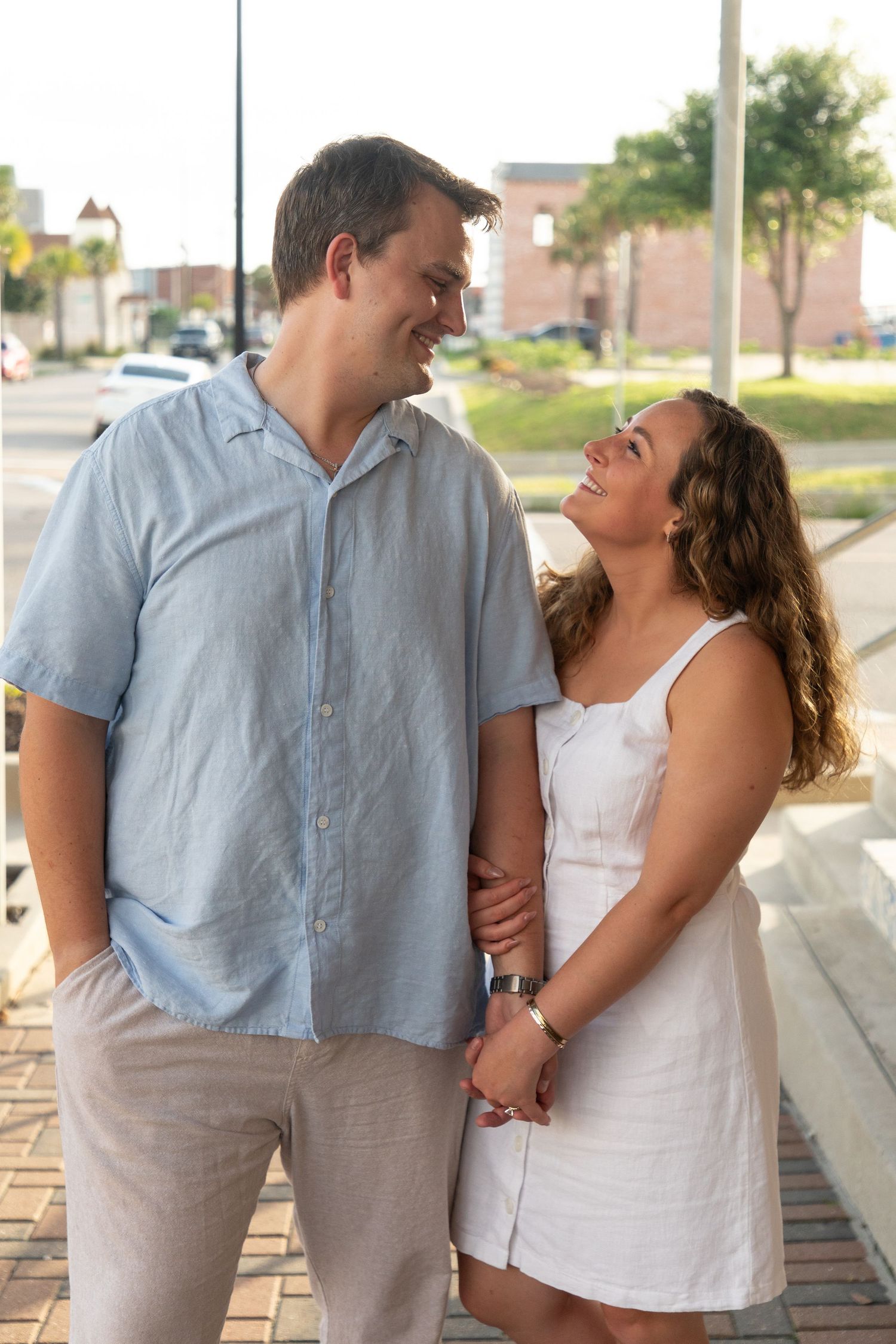 A couple in casual attire share romantic moments along a brick walkway in a series of candid photos.