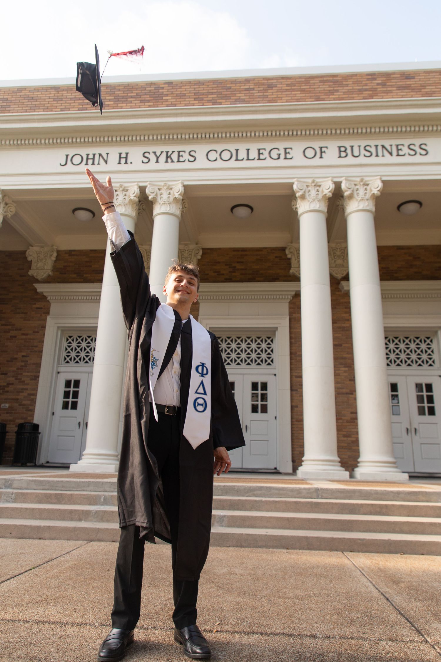 Graduation photos in front of John H. Jones College of Business building with classical columns.