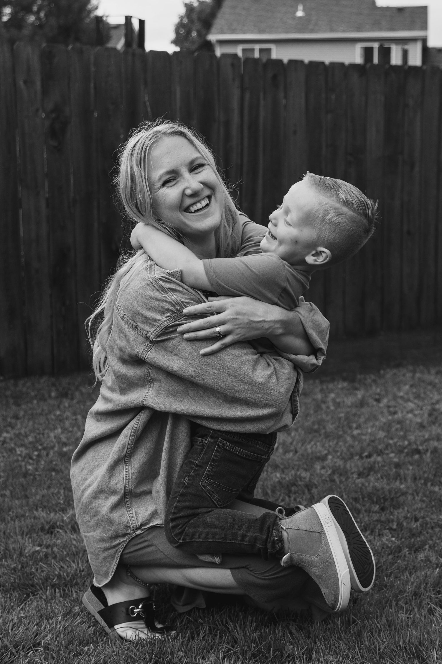 Black and white photo of joyful moment shared between two people on grass.