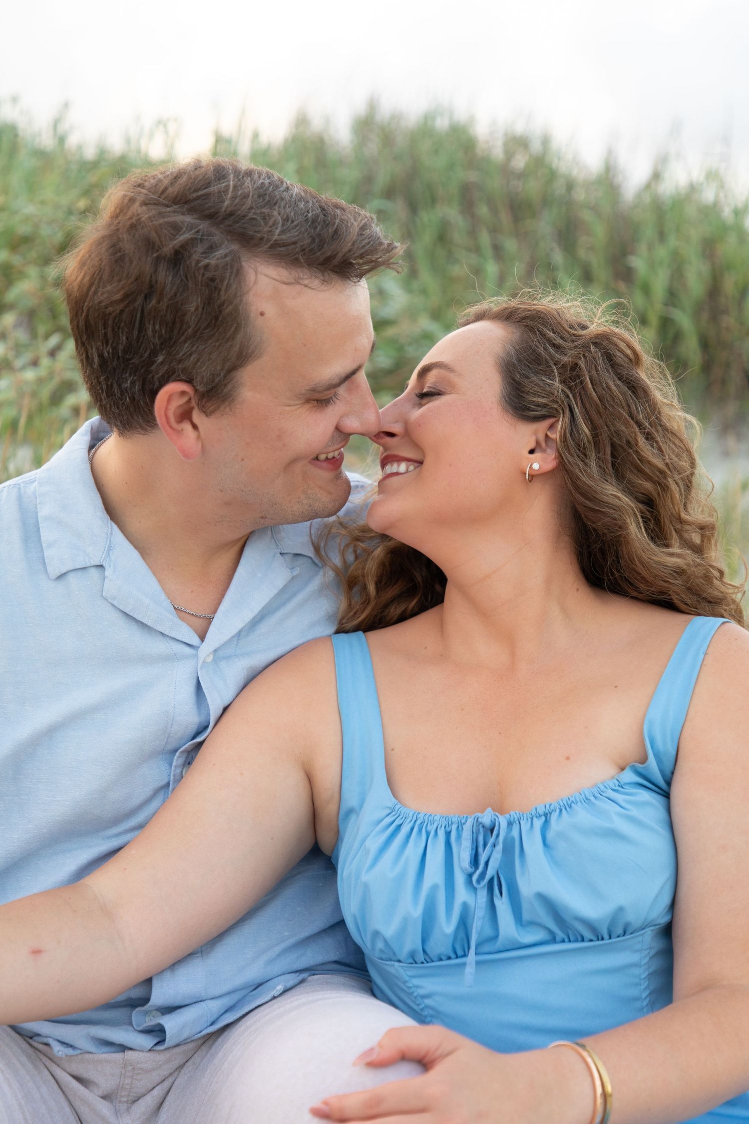 A couple shares an intimate moment while relaxing outdoors in casual summer attire.