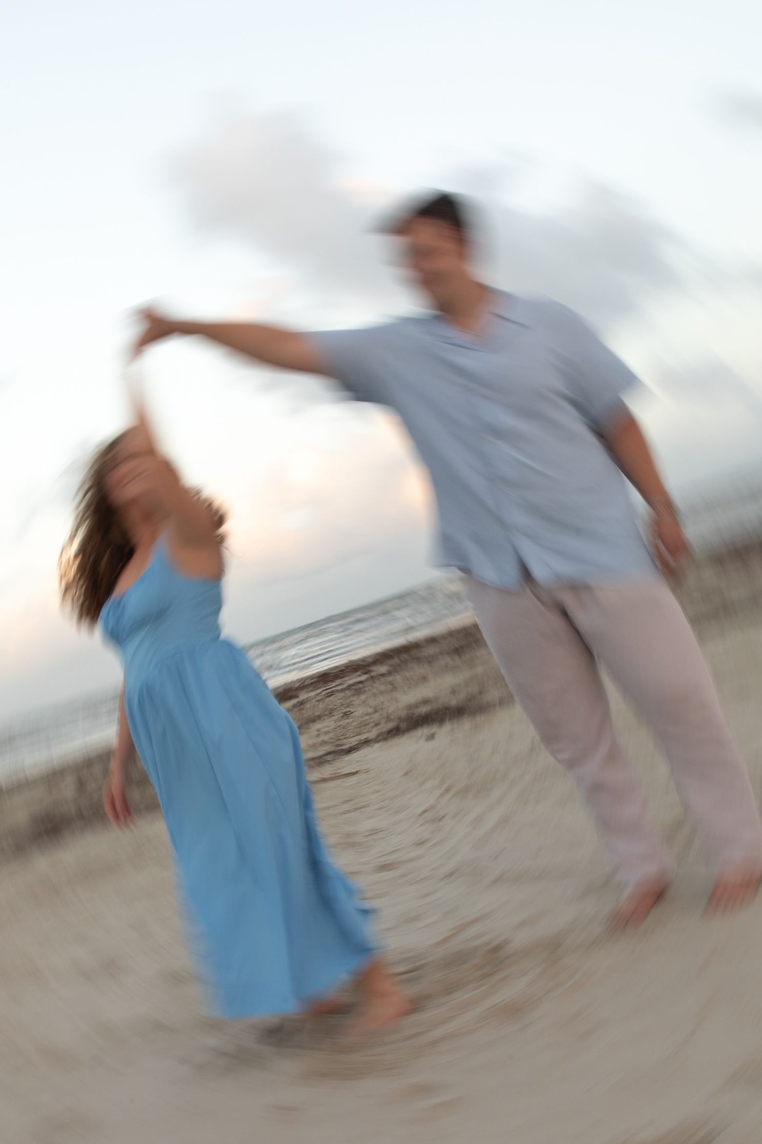 Motion-blurred figures dancing on a beach at sunset.