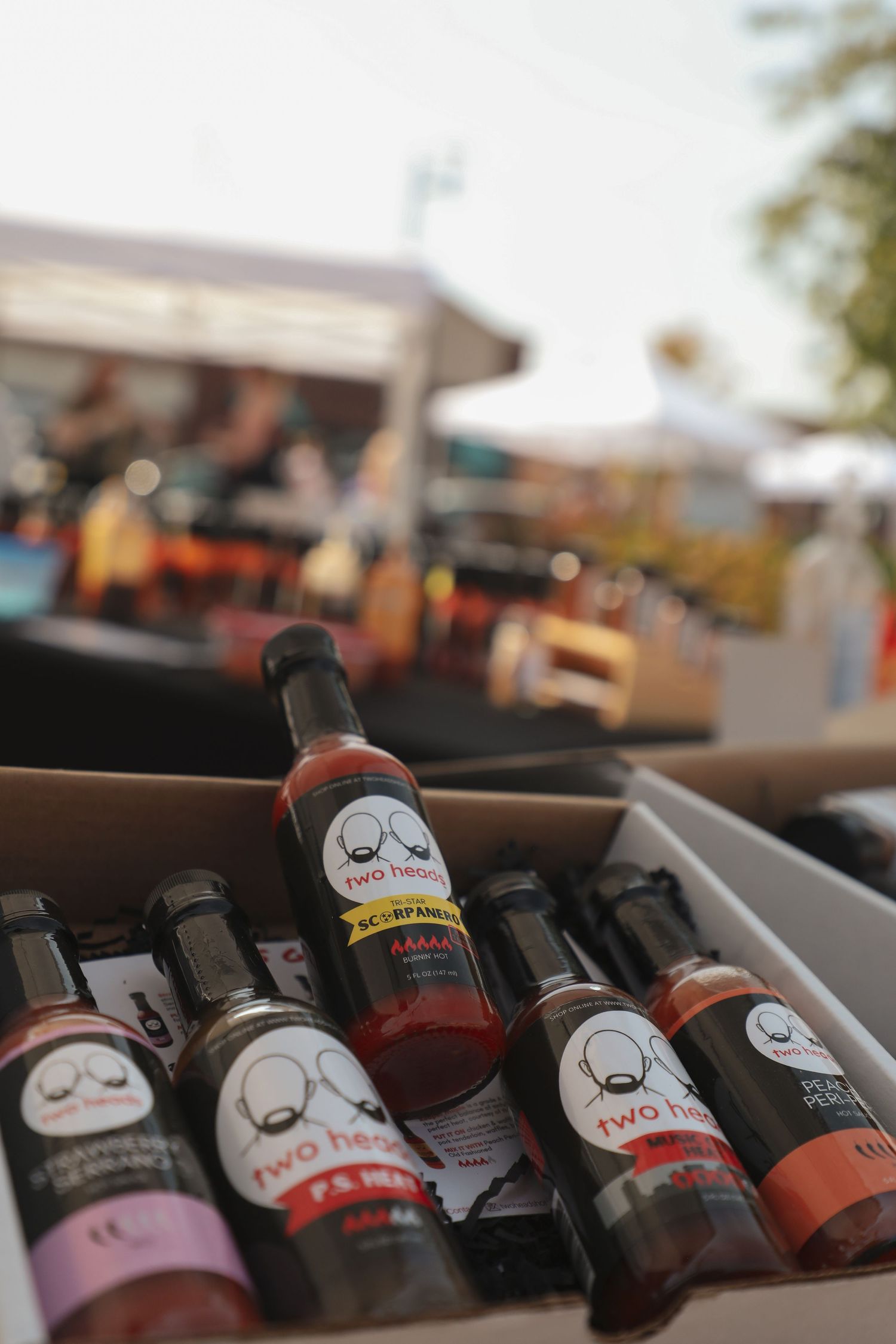 Artisanal bottled sauces with whimsical face logos displayed in retail setting.