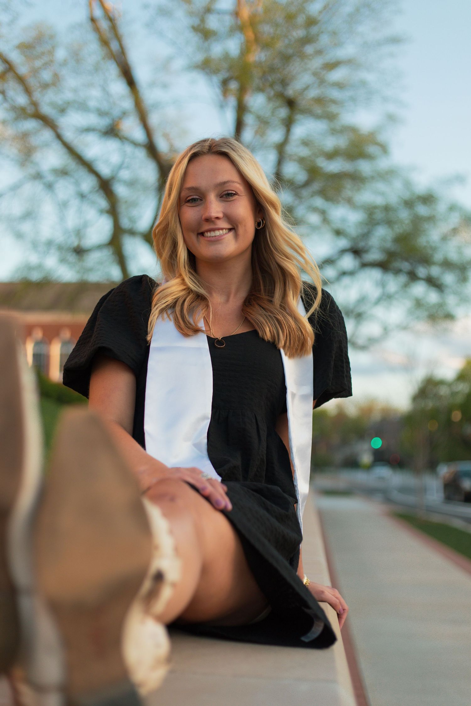 Graduate celebration photo sequence with black and white outfit against urban background.