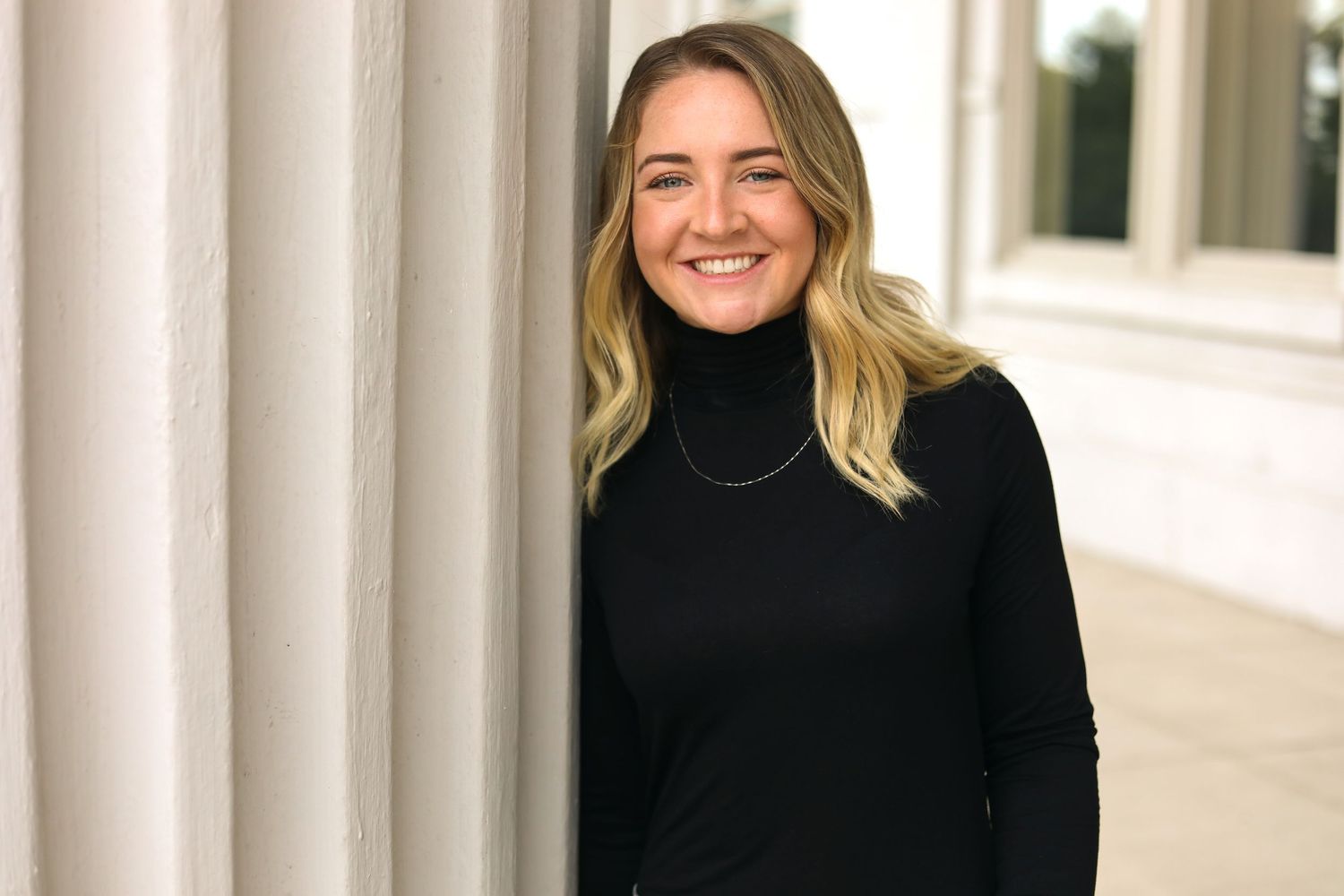 Professional headshots against white architectural columns in natural lighting.