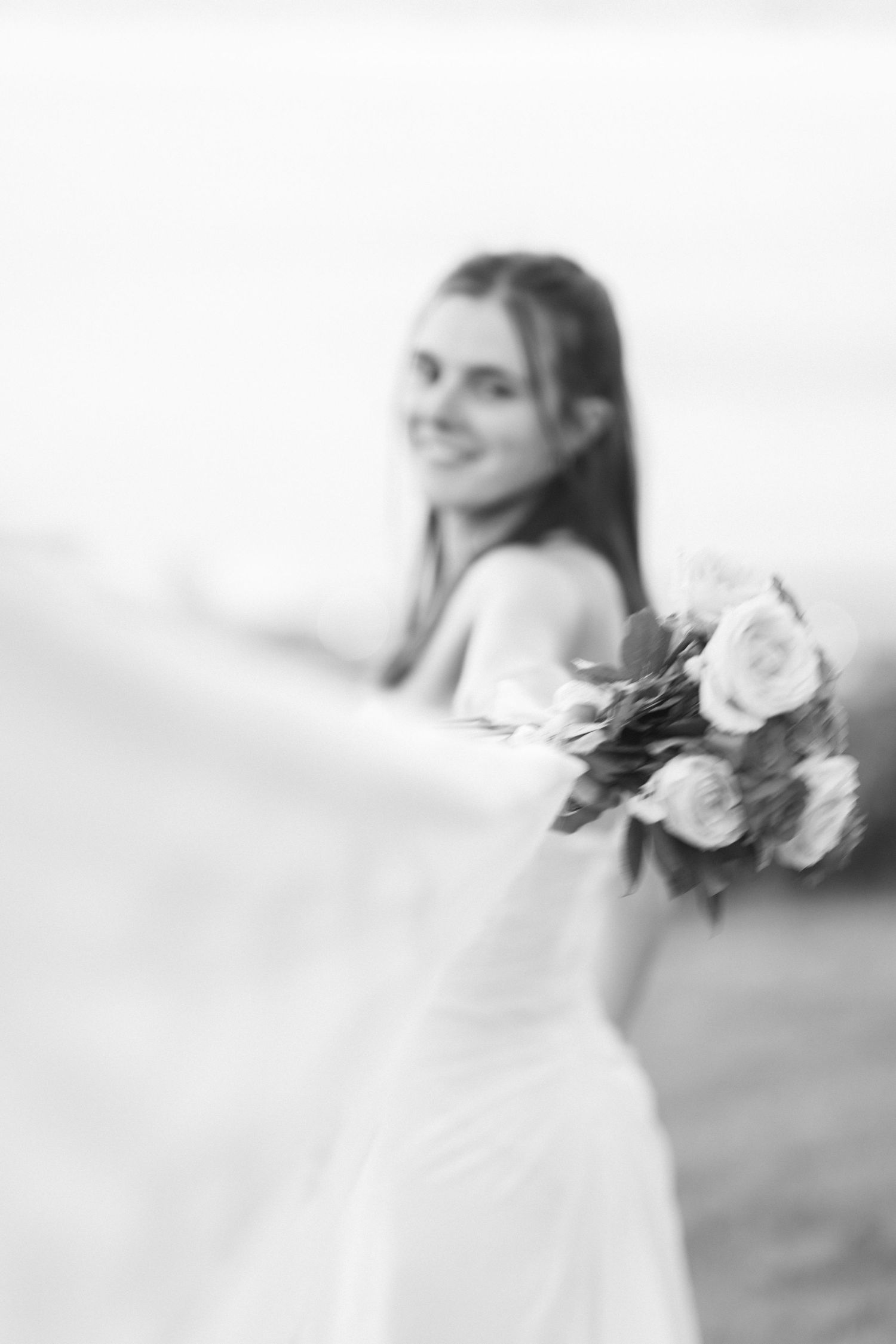 Artistic black and white photo of bride holding bouquet with roses.