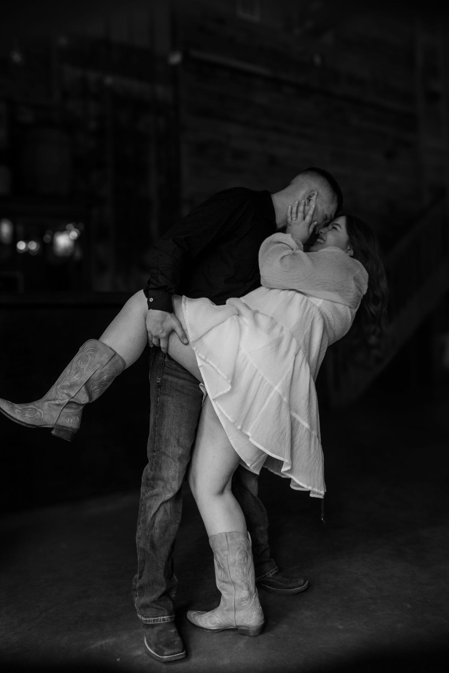 Black and white romantic photo of man lifting woman in a passionate embrace.