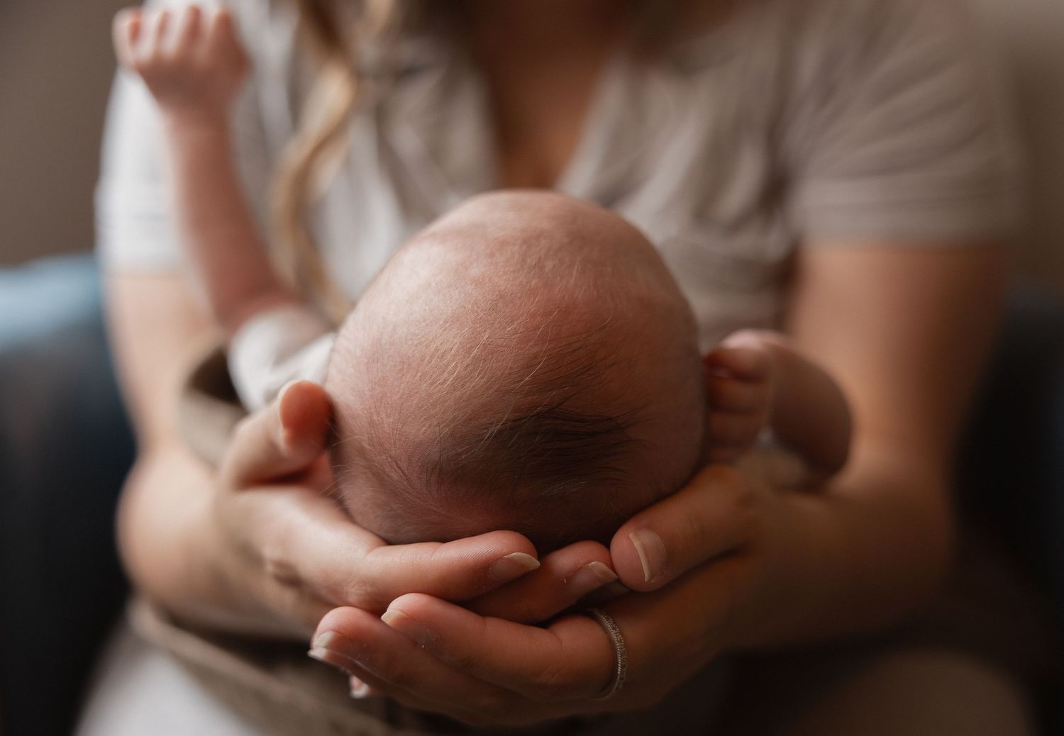 Newborn baby cradled gently in mother's hands during professional photo session.
