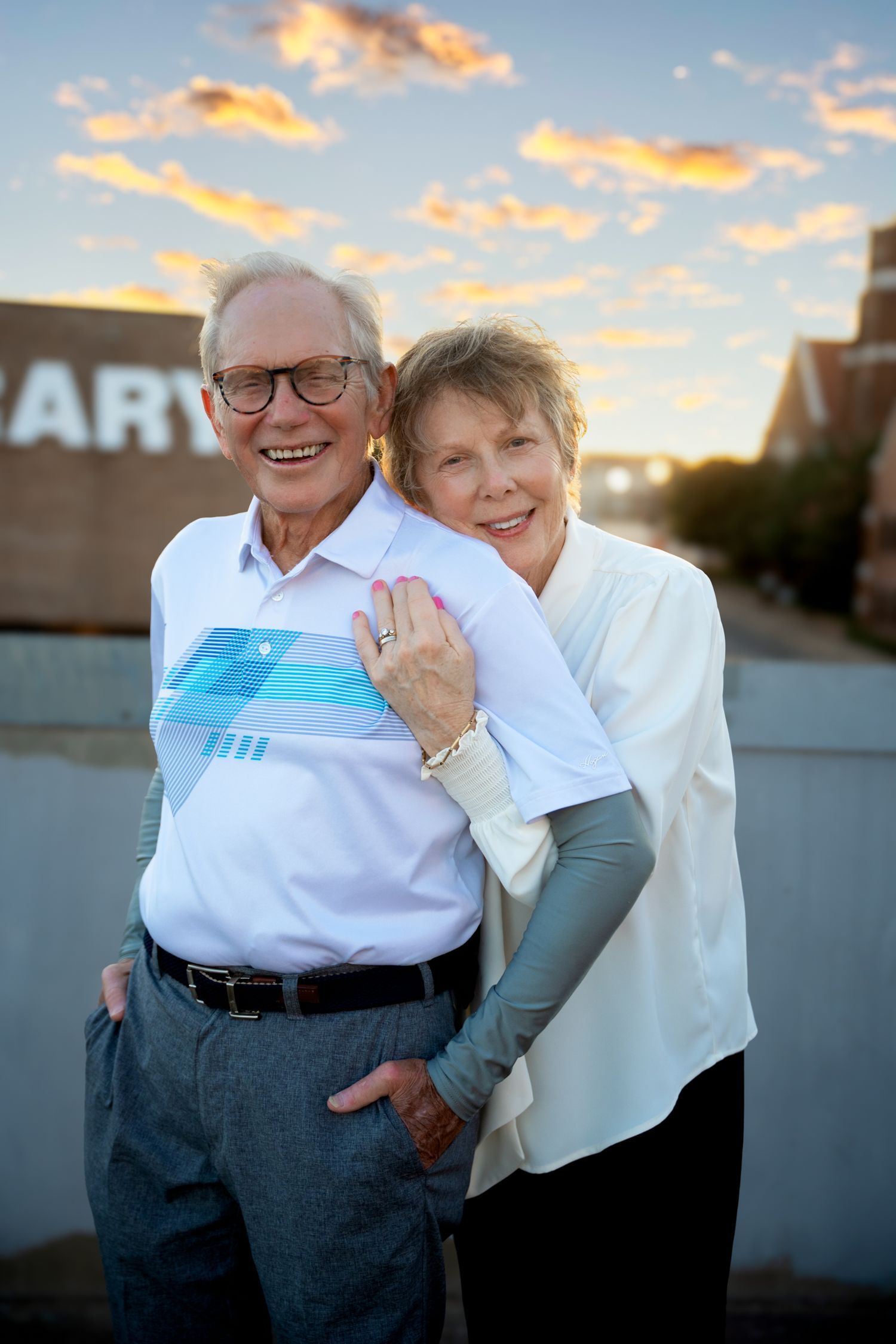 Happy senior couple embracing and smiling at sunset outdoor portrait session.