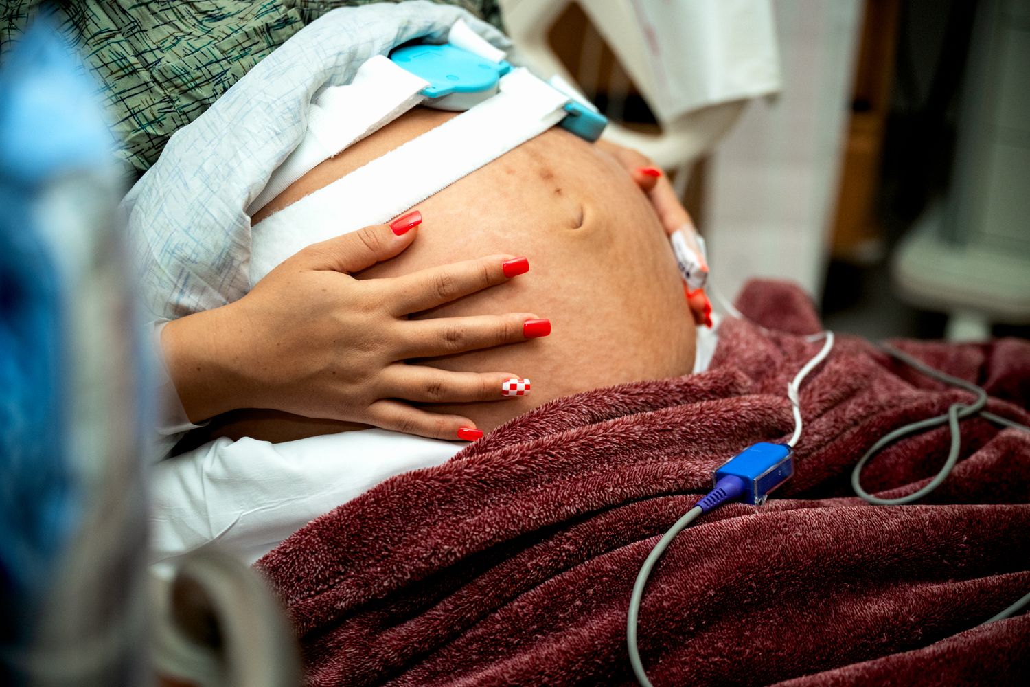Pregnant woman in hospital with fetal monitor attached to belly during labor.