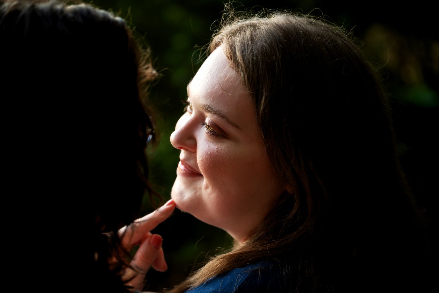 Close-up portrait of young girl smiling in dappled natural sunlight.