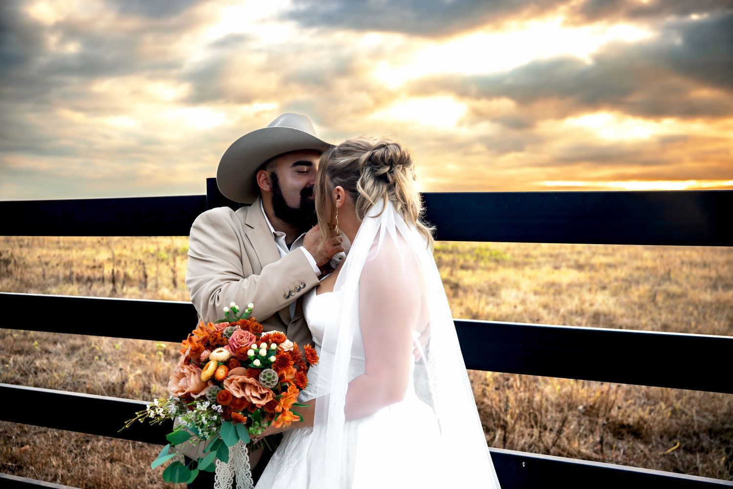 Bride and groom sharing a romantic moment at sunset on a ranch, with cowboy hat and fall bouquet.