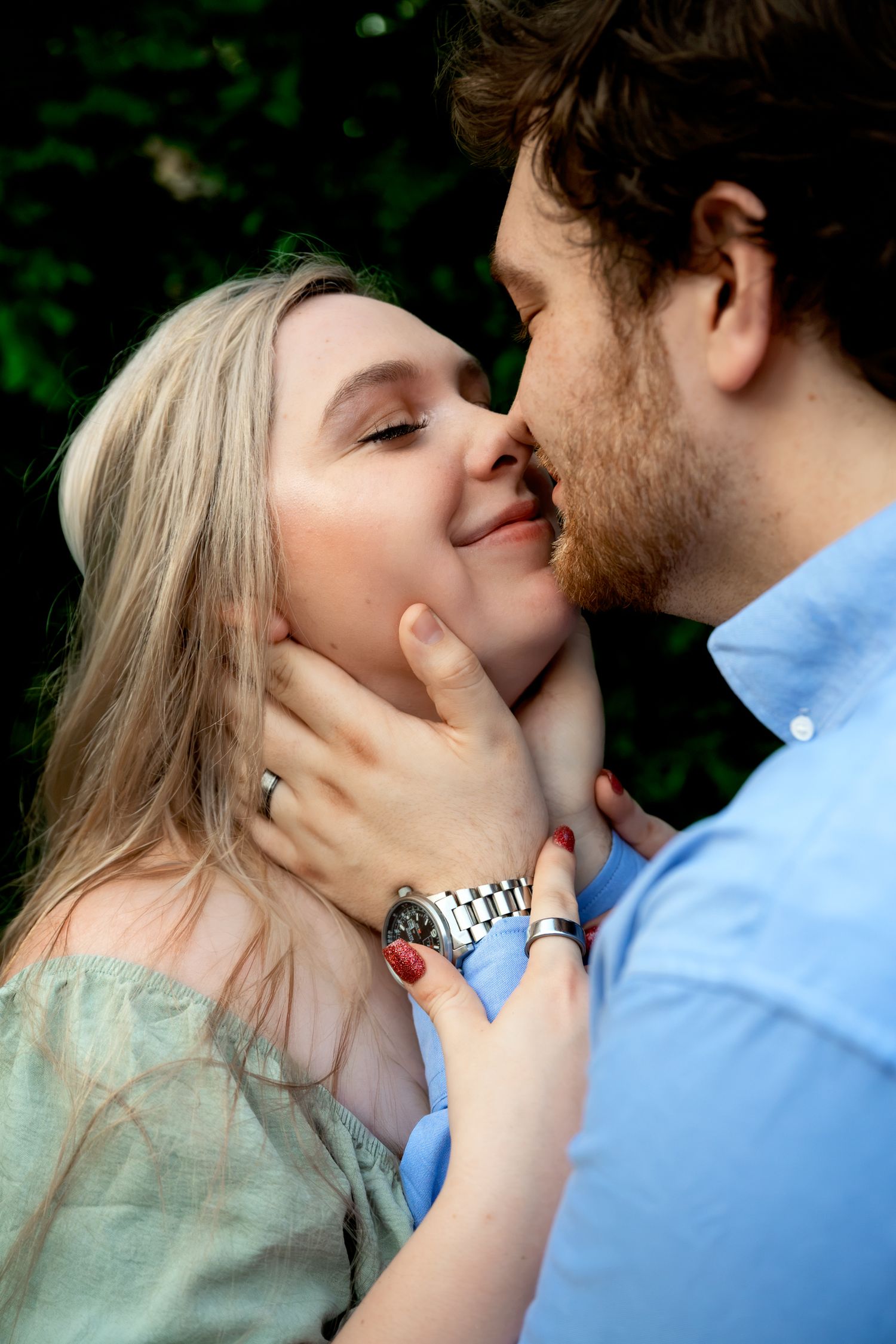 Romantic couple sharing tender kiss outdoors with man gently cradling womans face.