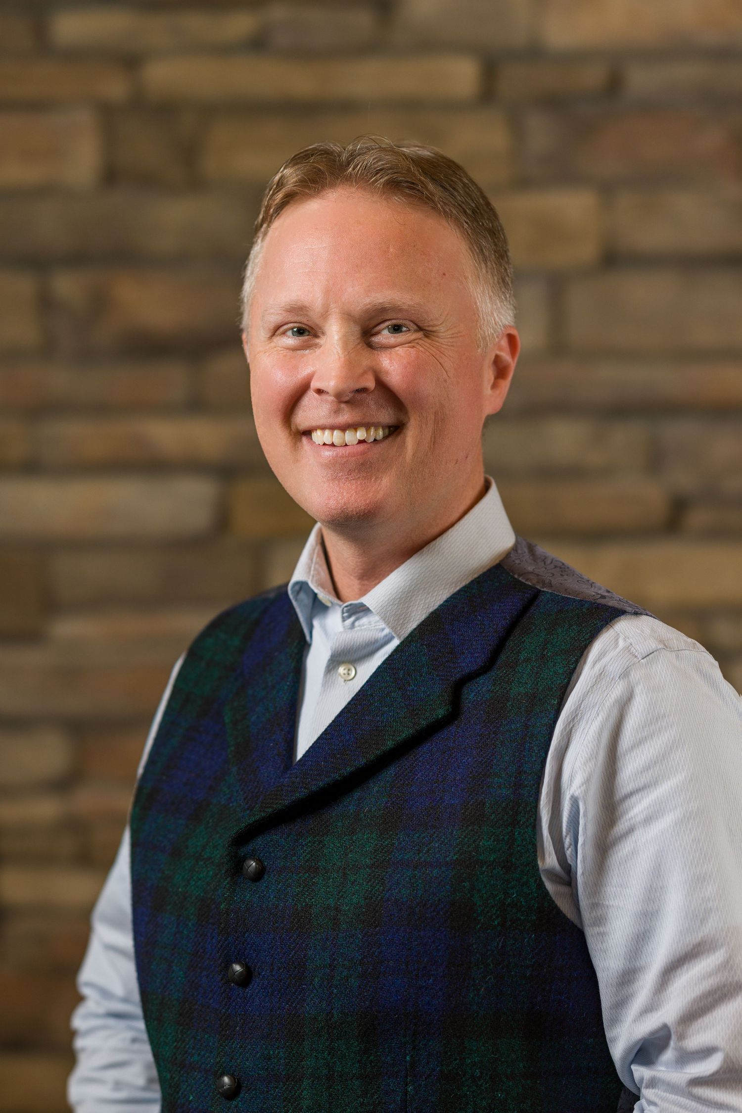 Professional portrait against stone wall backdrop.