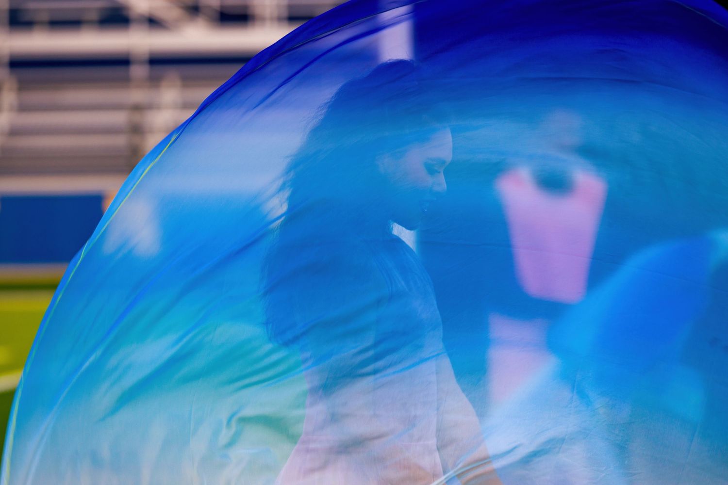 A row of clear soap bubbles float through the air with a bright blue sky in the background.