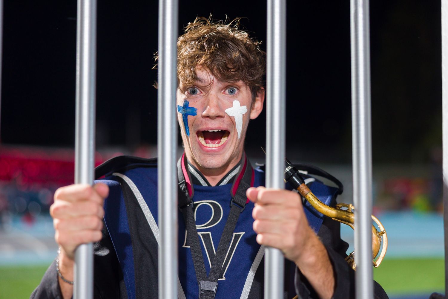 Hockey player smiles while gripping the bars of a penalty box during a game.