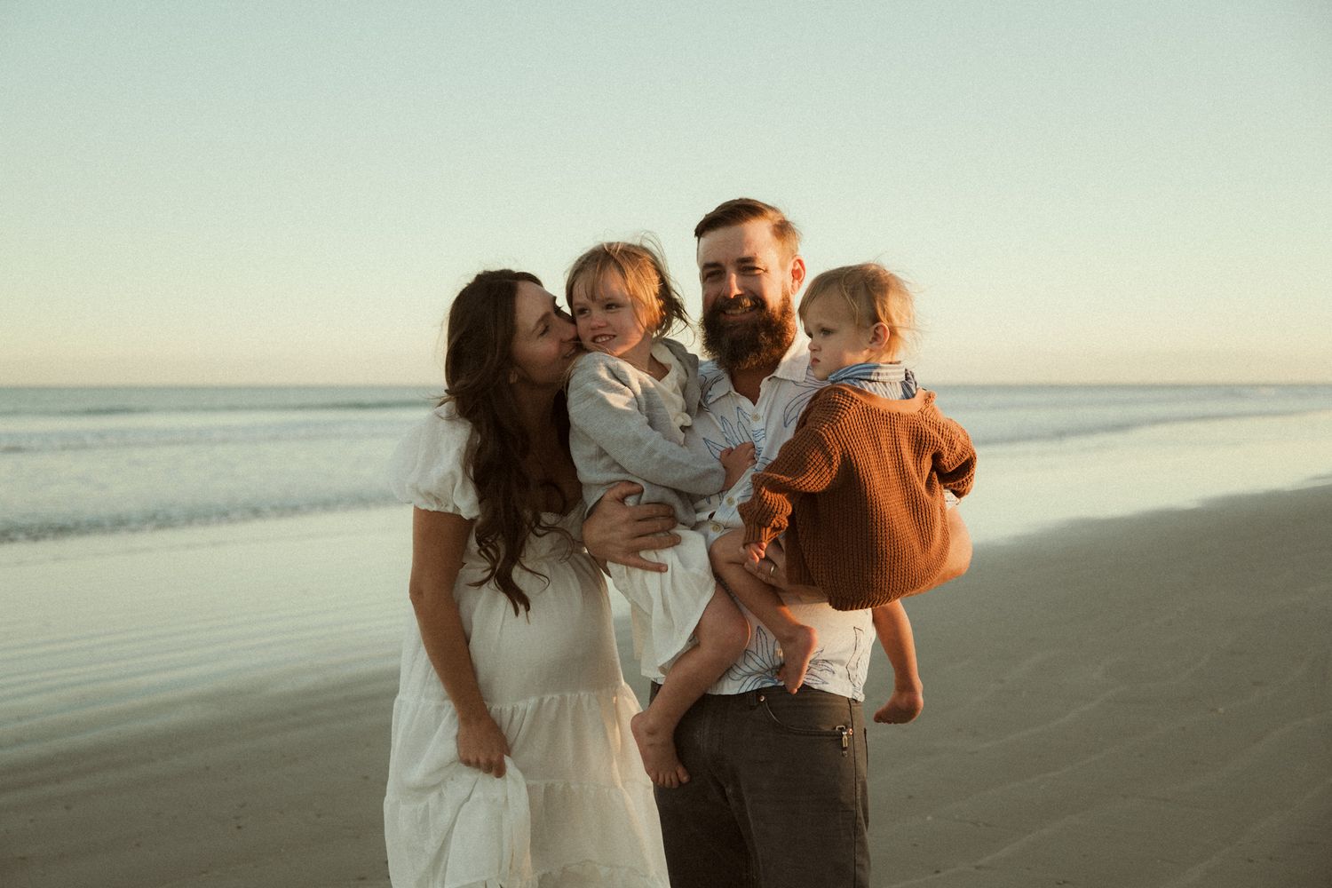 Family enjoying a sunset walk together along a peaceful beach shore.