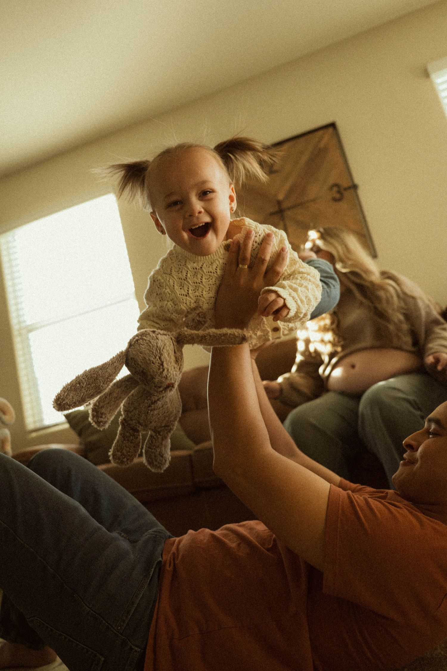 A sequence of photos shows a baby lying on a couch while playing with a stuffed toy bunny in warm lighting.