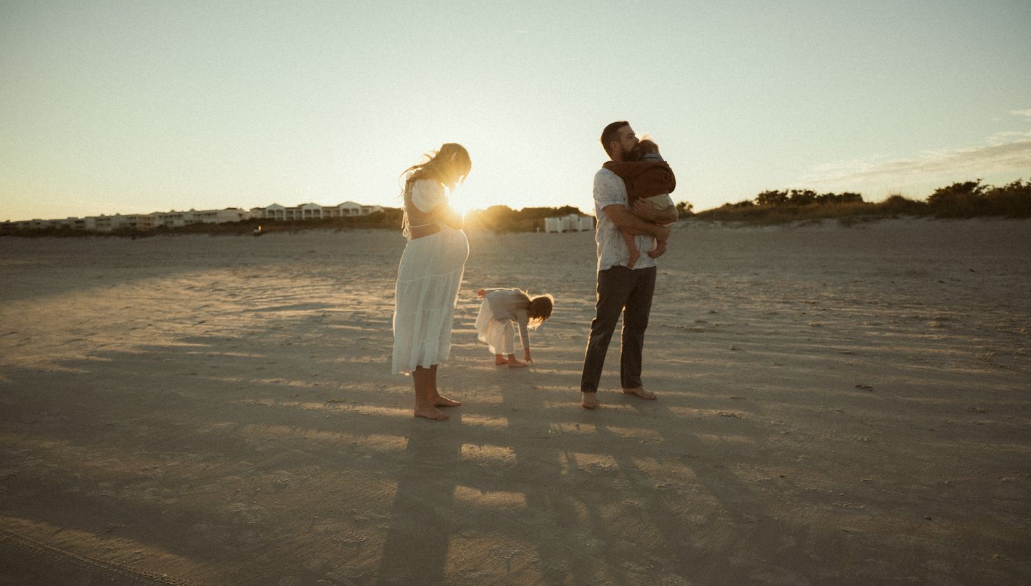 family with kids and one on the way enjoying golden hour at the beach