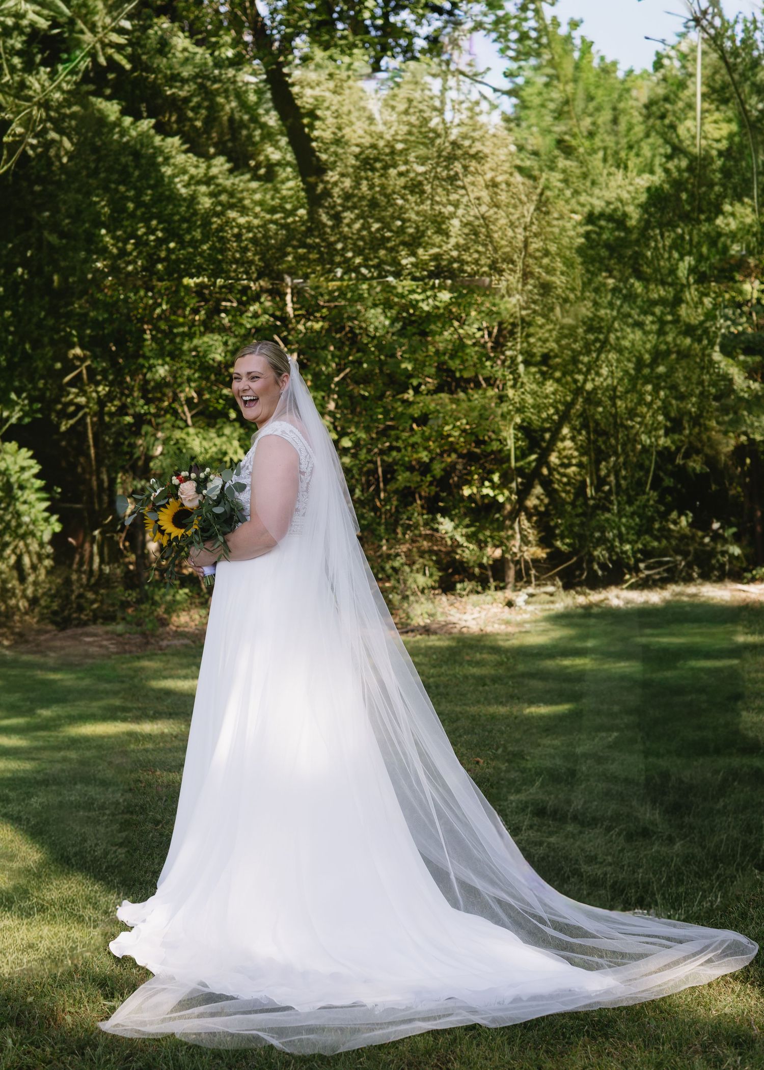 Wedding dress with flowing veil captured in outdoor garden setting.