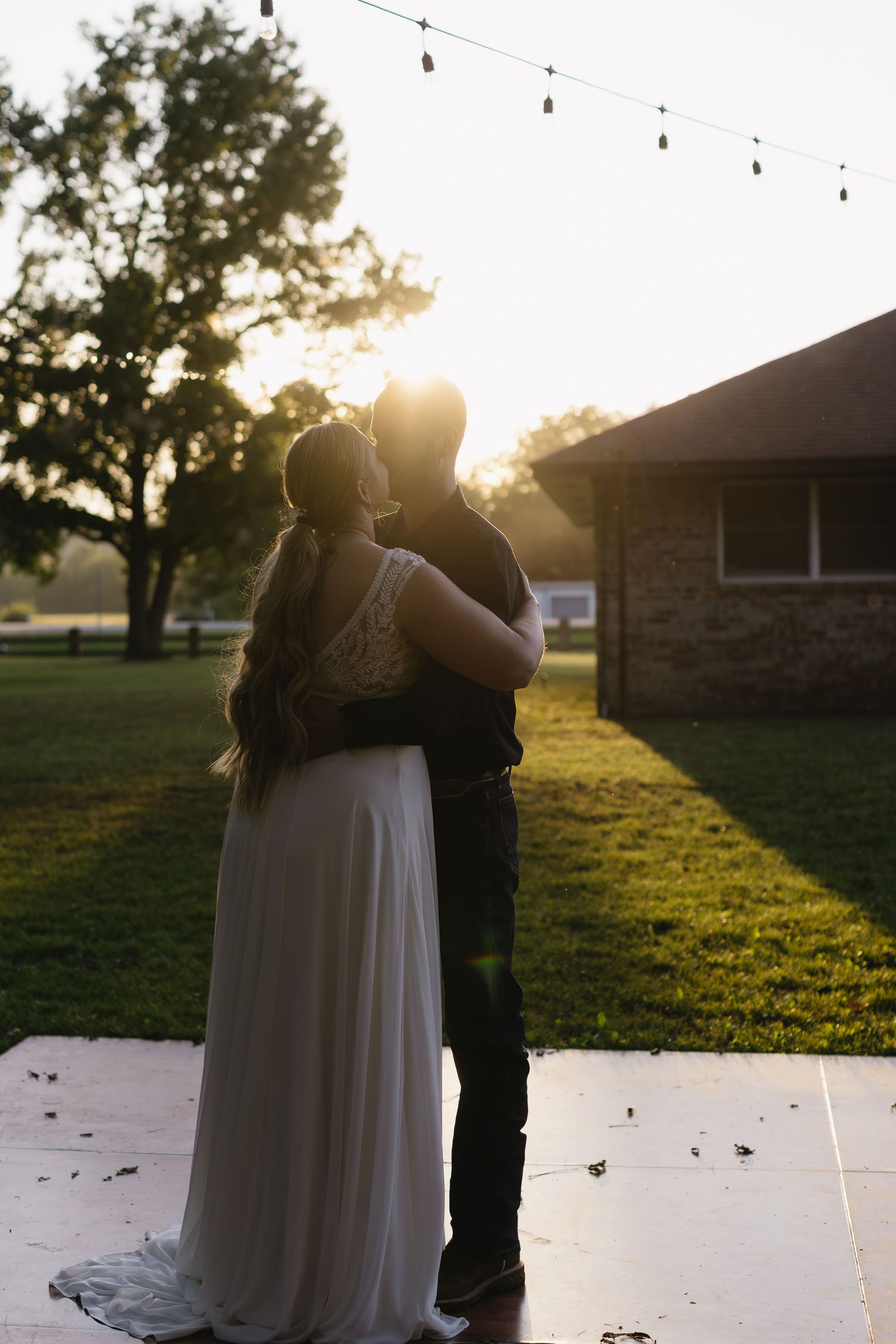 Sunset wedding dance with string lights glowing overhead.