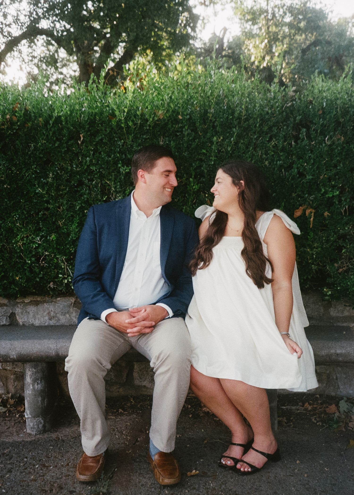A series of romantic photos showing a couple sitting on a stone bench in a garden setting, sharing sweet moments together.