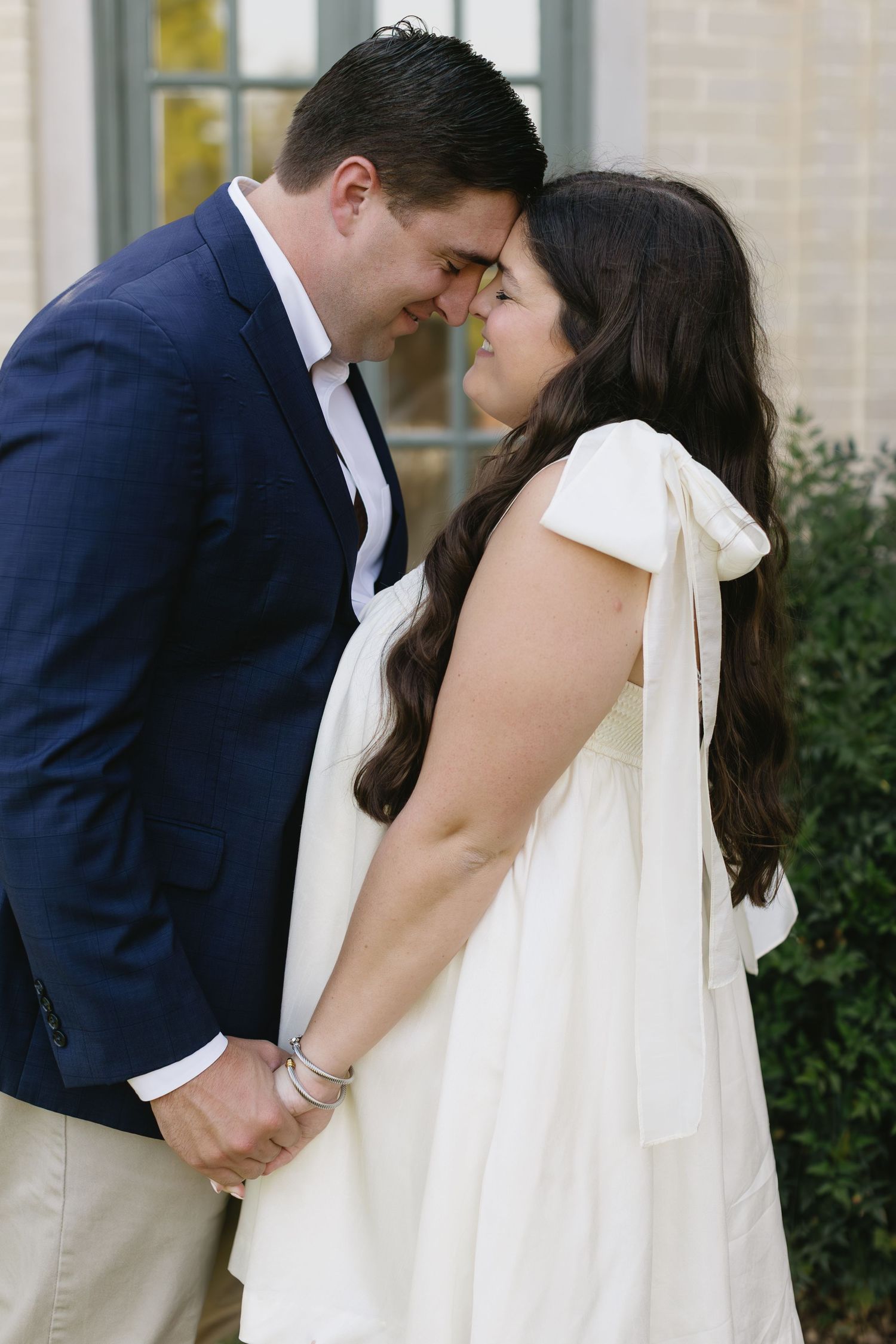 Romantic close-up shots of a couple sharing tender moments in front of garden shrubbery.