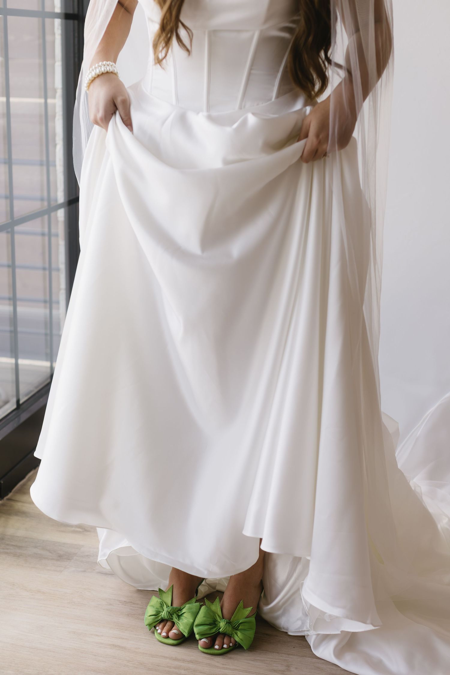 White wedding dress detail with green shoes peeking out from beneath the hem.