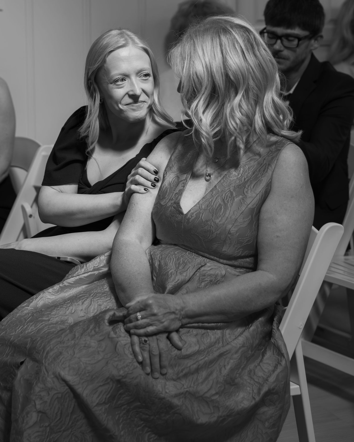 Black and white candid moment of guests seated at wedding celebration.