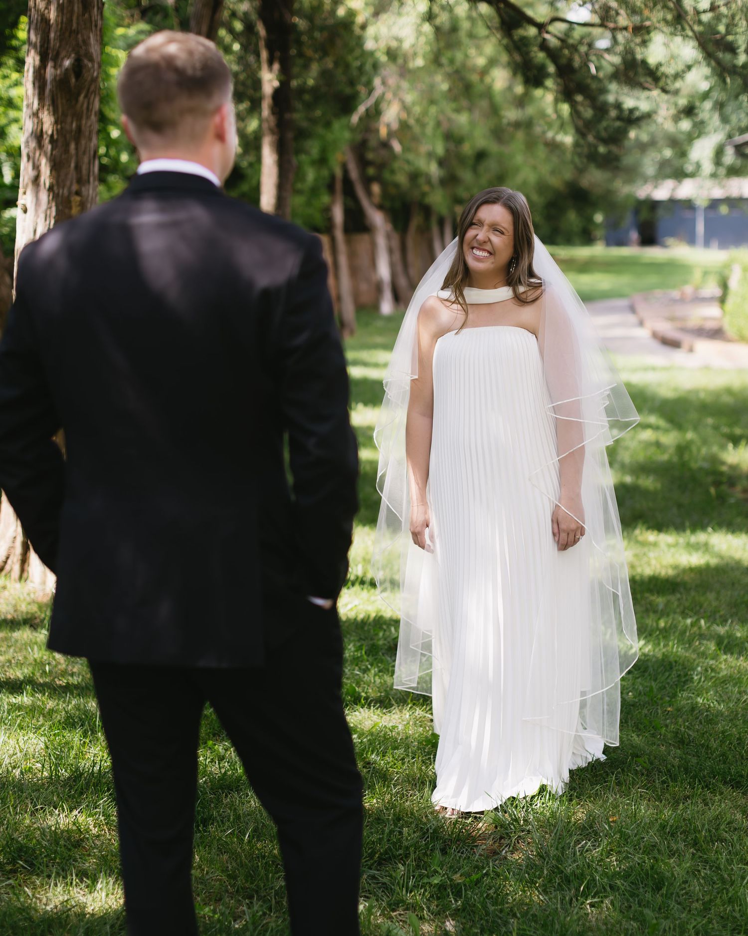 Wedding couple walking together on grass with bride wearing flowing white dress and long veil.