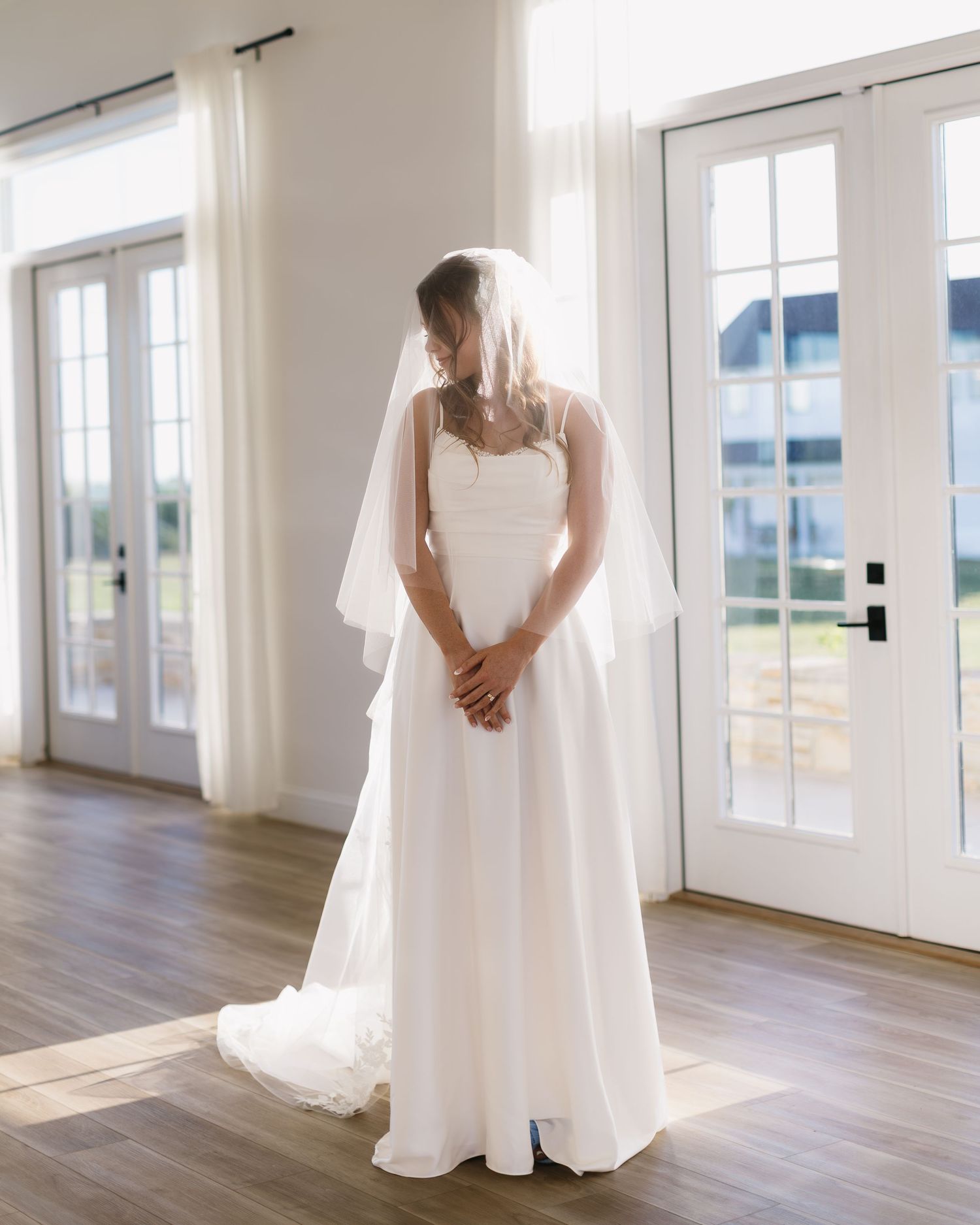 A series of elegant bridal portraits showing a flowing white wedding dress in a bright indoor space with hardwood floors.
