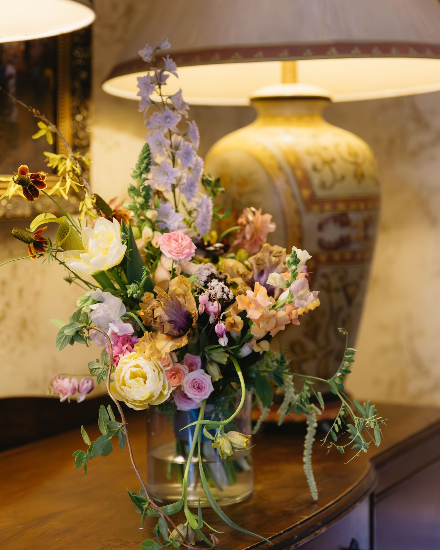 Romantic floral arrangements with pastel blooms and greenery displayed on wooden table.